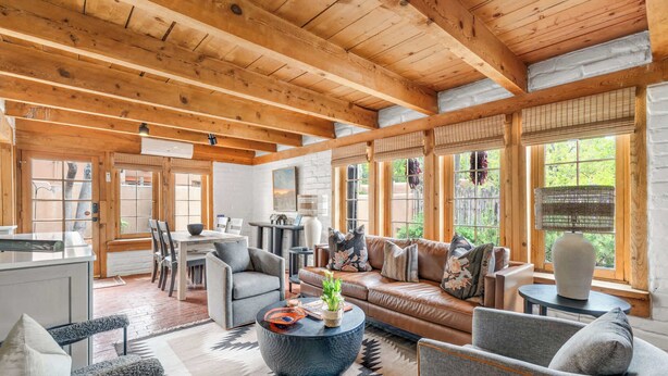 A spacious living area with a wooden ceiling, a sofa, a coffee table, and a dining area. - Luxury Home, Walk to Canyon Road, Historic Plaza (Santa Fe)