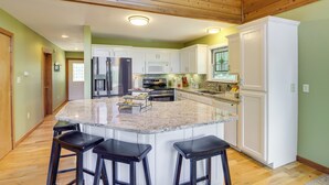 A spacious kitchen with a large island, wooden flooring, and white cabinetry. - Peaceful Greers Ferry Cabin w/ Deck & Lake View! (Greers Ferry)
