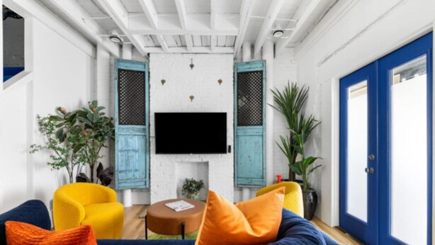 Een woonkamer met een bank, fauteuils, een salontafel en een televisie.