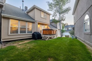 A two-story house with a covered deck, a grill, and a well-maintained lawn. - Oak Ridge Retreat | Hot Tub | Grill | Spacious (Cottonwood Heights)