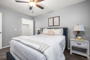 A bedroom with a bed, bedside tables, a ceiling fan, a door, and two framed motivational quotes on the wall. - Oak Ridge Retreat | Hot Tub | Grill | Spacious (Cottonwood Heights)