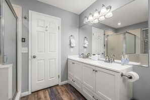 A bathroom with a double sink vanity, a large mirror, and a shower area. - Oak Ridge Retreat | Hot Tub | Grill | Spacious (Cottonwood Heights)