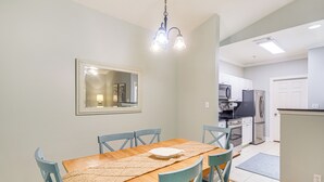 Een eethoek met een houten tafel, blauwe stoelen, een vloerkleed en een hanglamp.