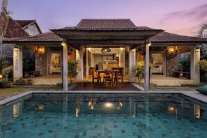 Una casa con piscina, zona pranzo e cucina.