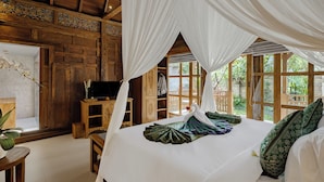 A bedroom with a canopy bed, wooden walls, and a TV on a wooden stand. - Uddhara Ubud Villa (Ubud)