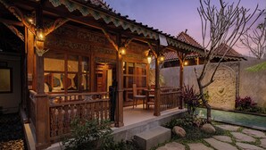 A traditional wooden building with a covered porch, stone steps, and a small garden area with rocks and plants. - Uddhara Ubud Villa (Ubud)