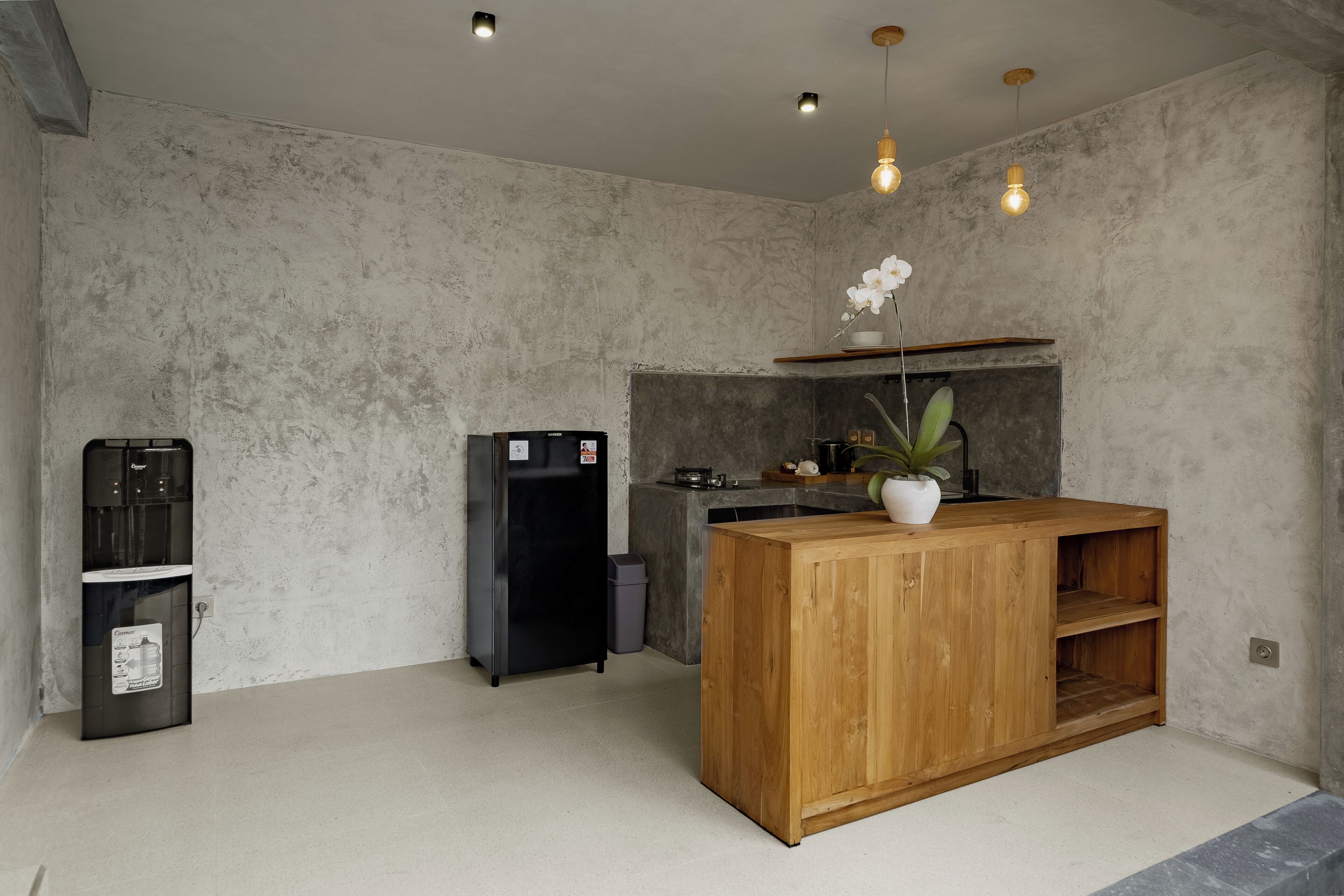 Una cocina moderna con una isla de madera, estufa integrada y un refrigerador negro.