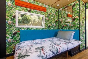Una habitación con una cama, una ventana y un espejo en la pared.