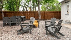 A patio area with Adirondack chairs, a table, and a yellow throw blanket. - Spacious 2BR Garden Suite in Denver Highlands (Denver)