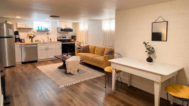 A compact living space with a kitchenette, a sofa, a dining table, and a small rug. - Spacious 2BR Garden Suite in Denver Highlands (Denver)