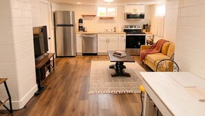 A compact kitchen with white cabinetry, a stainless steel refrigerator, a microwave, and a stove. - Spacious 2BR Garden Suite in Denver Highlands (Denver)