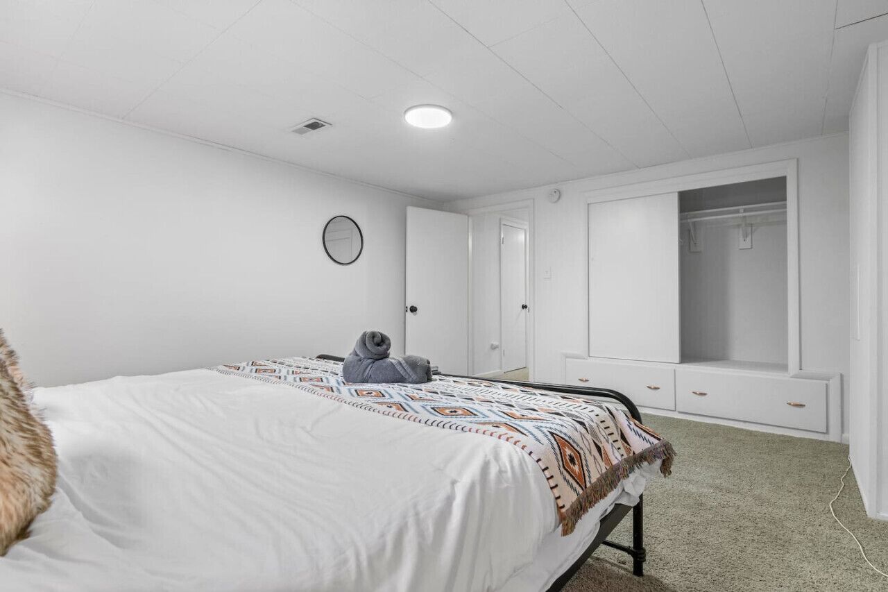 A bedroom with a bed, a wardrobe, a mirror, and a closet.