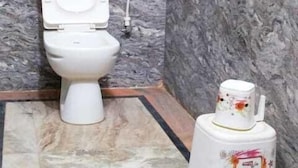 A bathroom with a toilet, a bidet, and a marble wall.