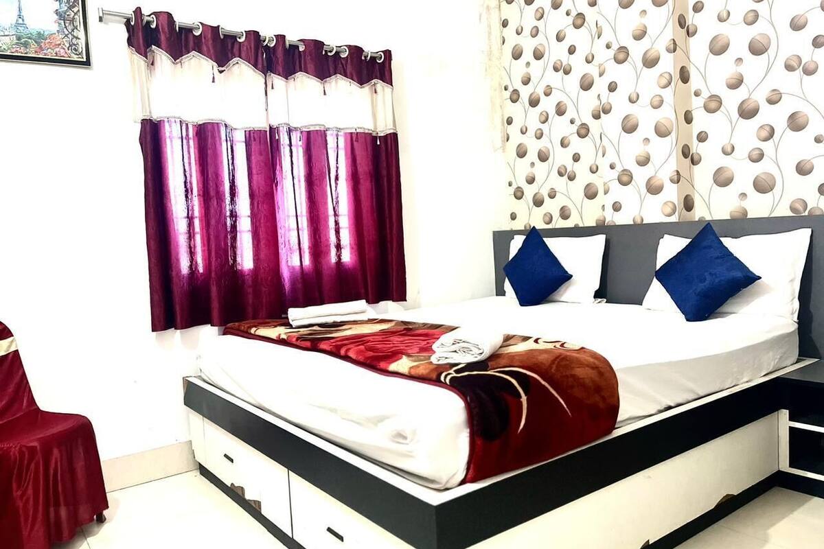 Ένα υπνοδωμάτιο με ένα κρεβάτι, ένα κομοδίνο, μια κόκκινη καρέκλα και έναν τοίχο με σχέδια.