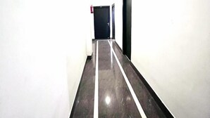 A long, narrow hallway with white walls and a dark floor.