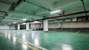 Un vaste espace de stationnement intérieur offrant de nombreuses places, avec des piliers blancs et un revêtement de sol vert.