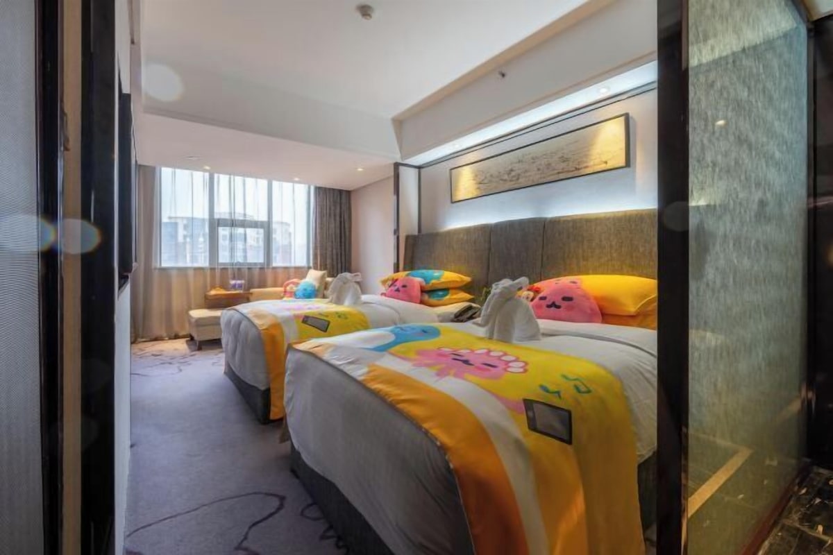 A hotel room with two beds, a large window, a headboard with a picture, and a carpeted floor.