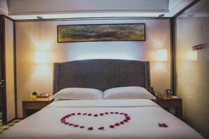 A hotel room with a bed, two bedside lamps, a painting above the bed, and a heart-shaped decoration on the bed. - Starshar (Changsha)
