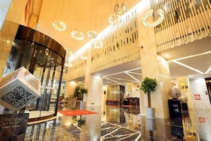 A modern lobby with a glass elevator, a QR code on a cube, and a reception desk. - Starshar (Changsha)