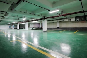 A multi-level parking garage with concrete pillars, green flooring, and yellow parking lines. - Starshar (Changsha)