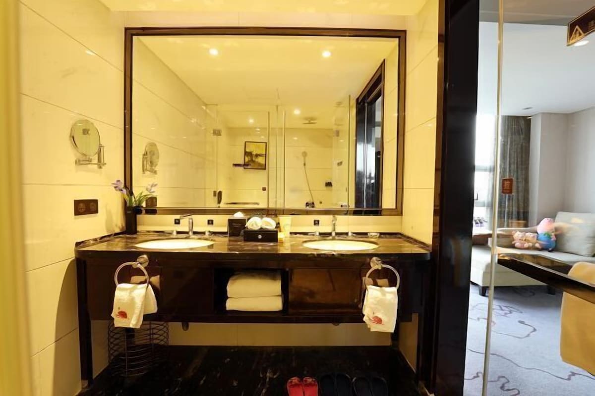A bathroom with two sinks, a large mirror, and a shower area.