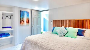 Un dormitorio con una cama grande, un armario, un cuadro en la pared y una puerta que da a otra habitación.