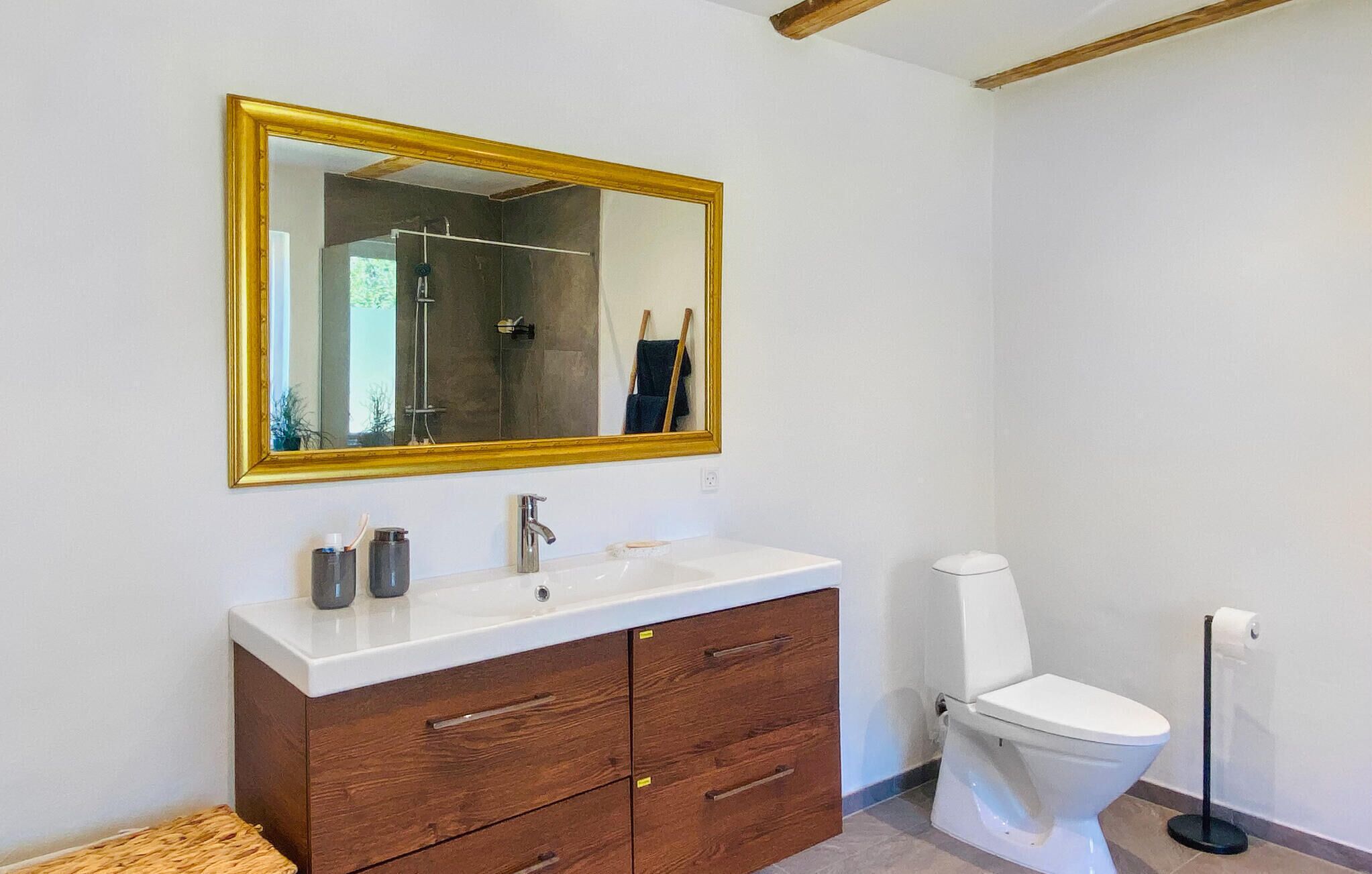 Un baño con lavamanos blanco, armario de madera y retrete.