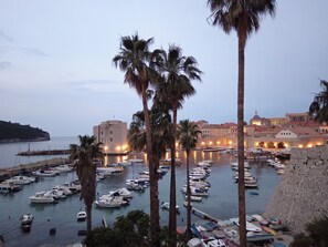 A marina with numerous boats docked, surrounded by palm trees and historic buildings.