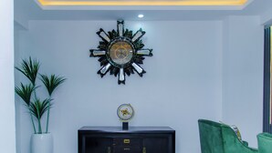 A room with a decorative wall clock, a black cabinet, and green chairs. - 3 Bed Home Sleeps 6 - Garden, Parking, Wifi (Ibadan)