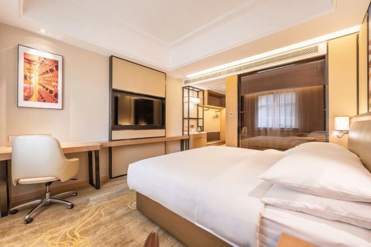 Una habitación de hotel con cama, escritorio, silla y televisor.