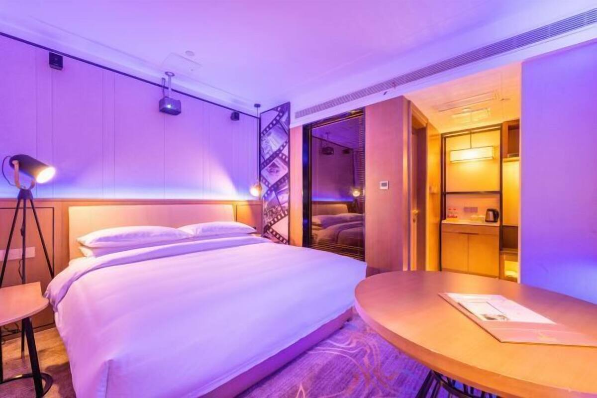 A hotel room with a bed, bedside table, and a small seating area.