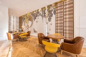A modern interior with a herringbone wooden floor, leather chairs, and a large wall mural.