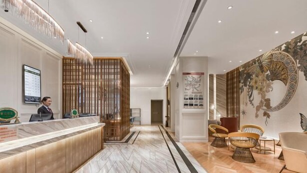 A hotel reception area with a marble reception desk, a wooden partition, and a wall with a decorative mural. - Vienna International Hotel (Xi'an Bell and Drum Tower Ximen Airport Bus) (Xi'an)