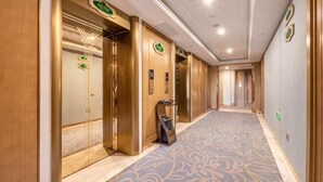 A hotel corridor with elevators, a reception desk, and a patterned carpet. - Vienna International Hotel (Xi'an Bell and Drum Tower Ximen Airport Bus) (Xi'an)
