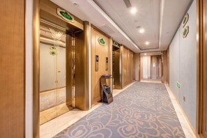 A hotel corridor with elevators, a reception desk, and a patterned carpet. - Vienna International Hotel (Xi'an Bell and Drum Tower Ximen Airport Bus) (Xi'an)