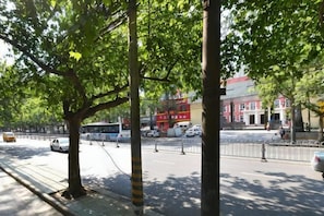 A street with trees, a sidewalk, and buildings in the background. - Vienna International Hotel (Xi'an Bell and Drum Tower Ximen Airport Bus) (Xi'an)