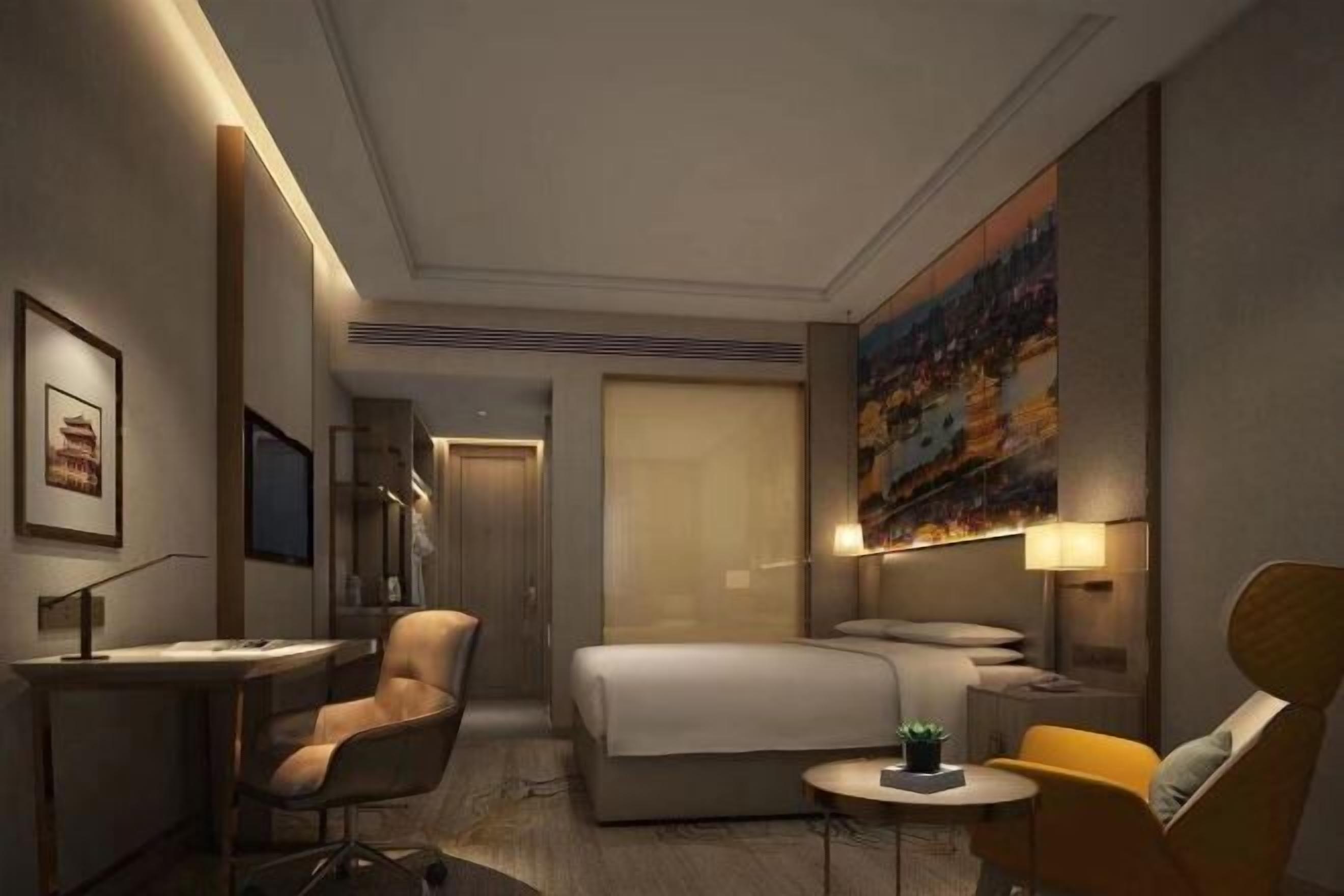 Habitación de hotel con cama, escritorio, sillas, una mesita y un cuadro en la pared.