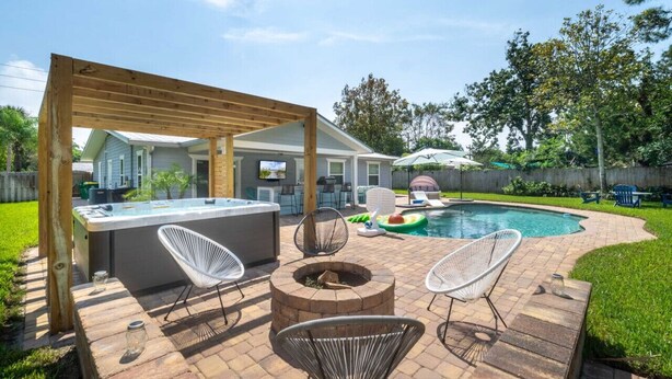A backyard with a hot tub, fire pit, and outdoor seating area. - Endless Summer Retreat (Jacksonville Beach)