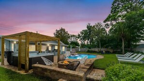 A backyard with a hot tub, fire pit, and lounge chairs. - Endless Summer Retreat (Jacksonville Beach)