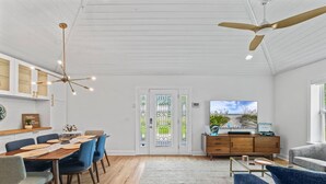 A spacious living area with a dining table, blue chairs, a sofa, a coffee table, and a television. - Endless Summer Retreat (Jacksonville Beach)