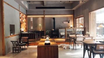 A cozy interior with a central wooden table, seating arrangements, and a fireplace.