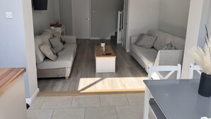 En moderne stue med to sofaer, et sofabord og et fjernsyn monteret på væggen.