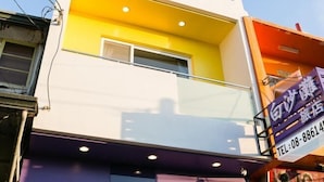 A multi-story building with a yellow and white facade, a visible window, and a sign with a phone number. - Baishatan Hotel (Pingtung)