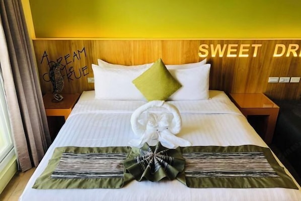 A neatly made bed with a green and white pillow, a white pillow, and a decorative bow on the bedspread. - Baishatan Hotel (Hengchun)