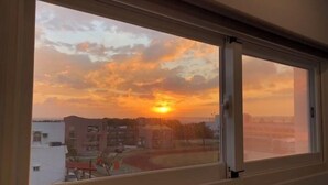 A view from a window of a building at sunset, with the sun setting behind a skyline of buildings. - Baishatan Hotel (Hengchun)