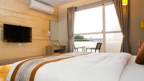 A hotel room with a bed, a TV, a desk, a chair, and a window with a view. - Baishatan Hotel (Hengchun)