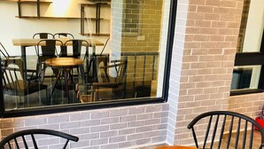 A cafe interior with brick walls, a large window, and a wooden table with chairs. - Baishatan Hotel (Hengchun)