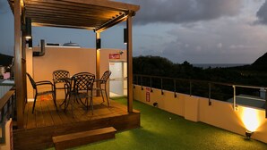 A deck with a pergola, chairs, and a small table, overlooking a scenic landscape. - Baishatan Hotel (Hengchun)