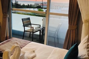 A hotel room with a bed, a chair, a small table, and a view of the cityscape through large windows. - Baishatan Hotel (Hengchun)