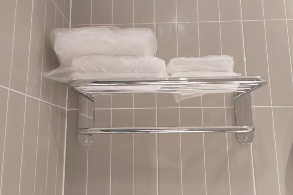 A bathroom with a towel rack holding several white towels.